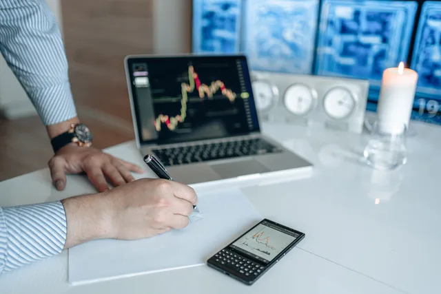 Man analyzing stock market trends on a laptop, writing notes on paper. What AI content operations measurement means for UK content teams