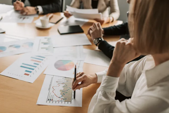 Business professionals reviewing charts and graphs during a meeting in office setting. Why an AI content operations product comparison needs a decision first