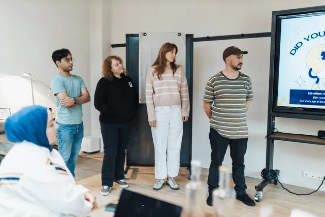 Diverse group of adults attentively watching a presentation in a bright modern office setting. Why AI content operations risk scenarios deserve a place in your planning