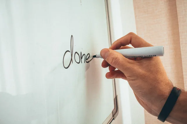 Crop unrecognizable male coach writing done word on whiteboard during presentation in light office. When to build an AI content operations strategy framework